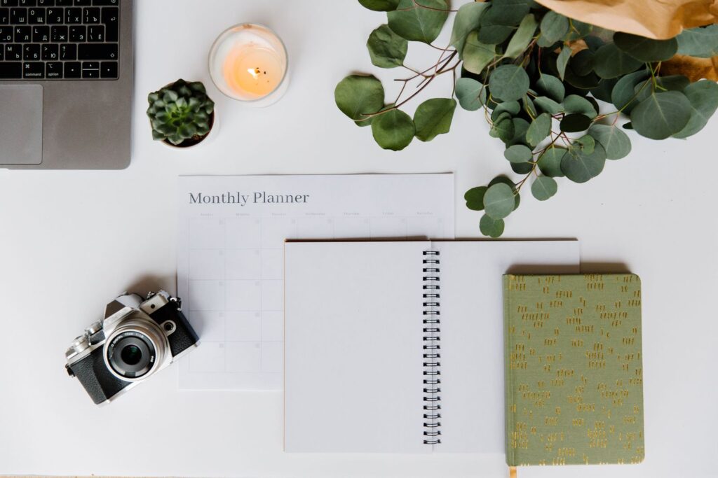 Mesa com planner, câmera, vela e folhagem, composição calma e simbólica — foto: Pexels
