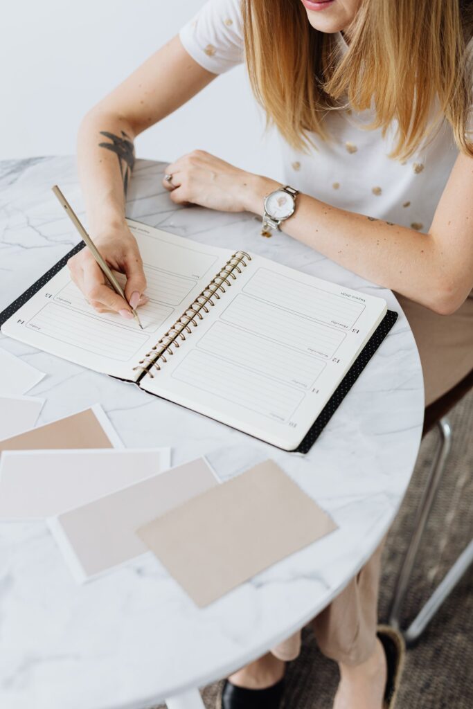 Mulher escrevendo em um planner sobre uma mesa clara, organizando a rotina com calma — foto: Pexels
