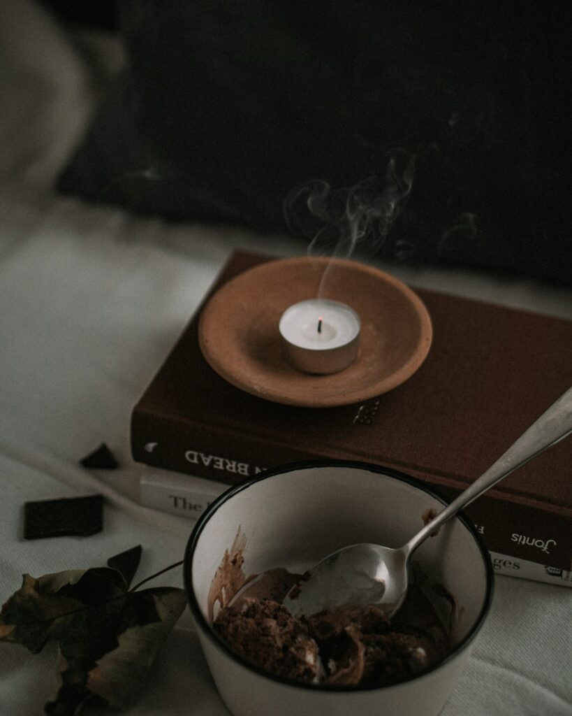 Pequena vela acesa sobre um livro, criando um ambiente calmo para um ritual de espiritualidade leve