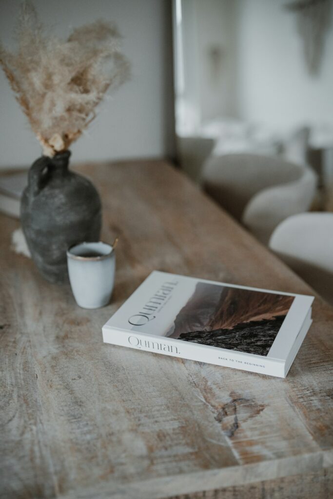 Livro aberto sobre uma mesa de madeira, ao lado de uma xícara de café