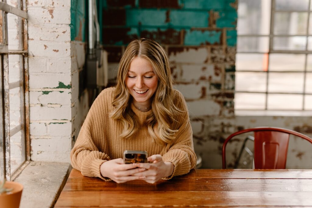 mulher sorrindo olhando para o celular em ambiente tranquilo