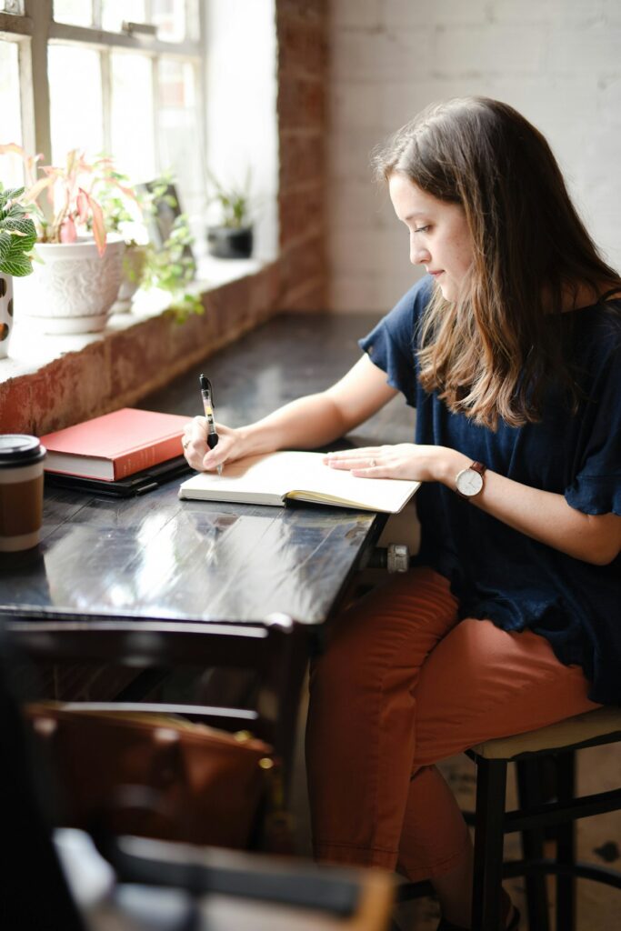 mulher escrevendo em caderno de anotações em mesa de trabalho