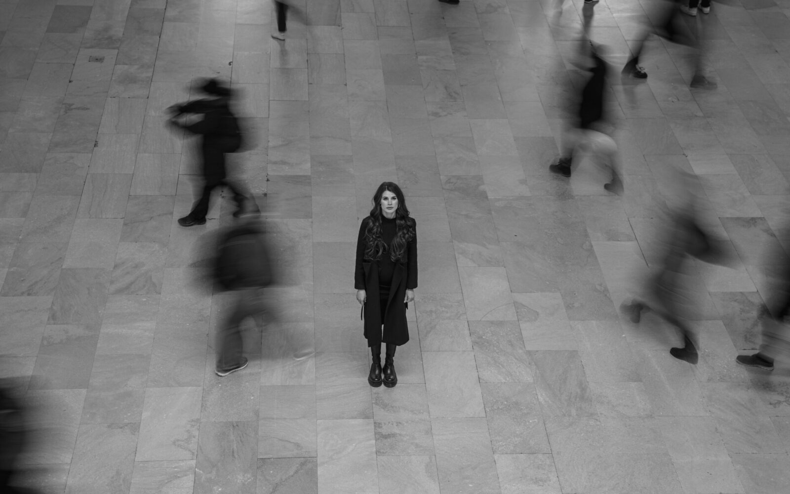 ansiedade social: mulher sozinha em meio a uma multidão desfocada, representando o medo de ser observada e julgada