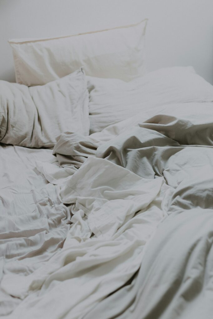 Cama com travesseiros e edredom macio, representando o cobertor pesado para relaxar e dormir melhor