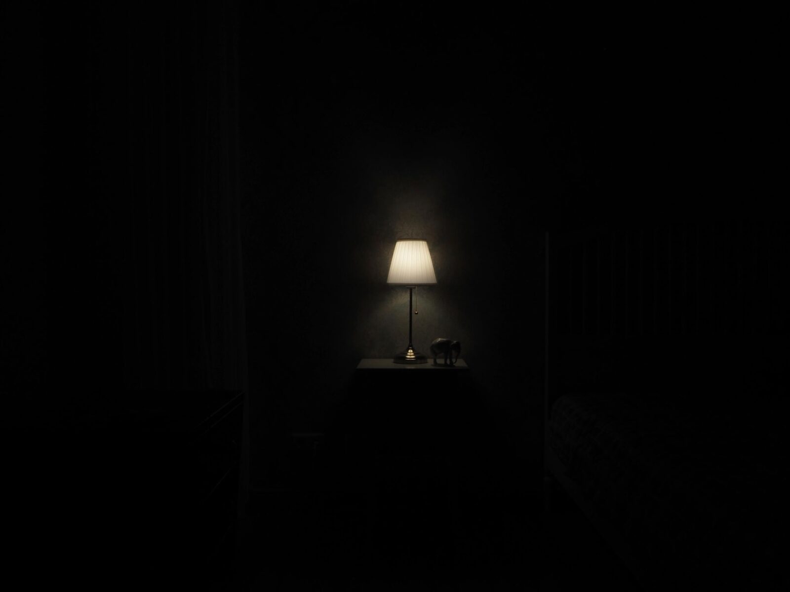 Máquina de ruído branco: quarto escuro com luminária acesa na mesa de cabeceira