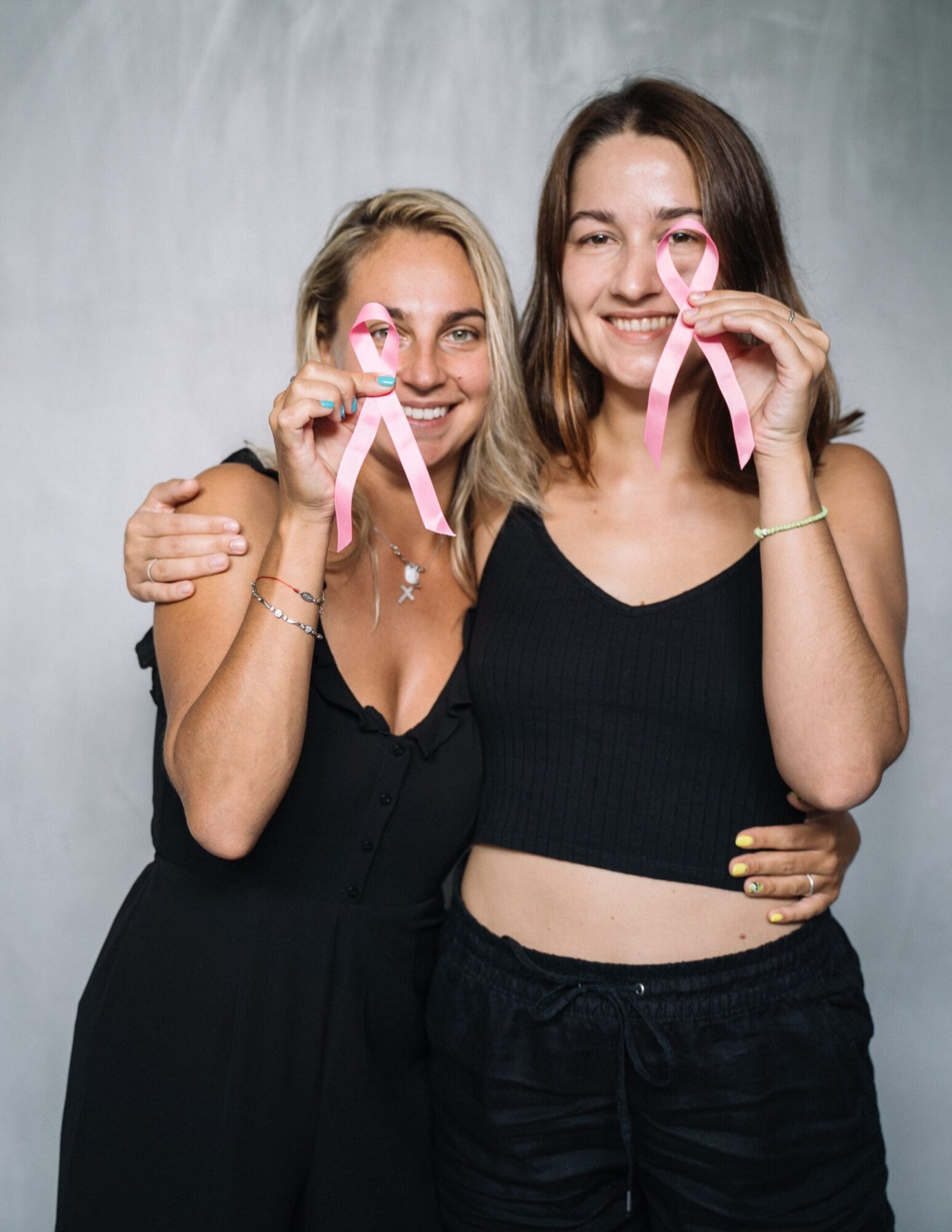 outubro rosa: duas mulheres se abraçando em apoio mútuo, segurando laços rosa de conscientização