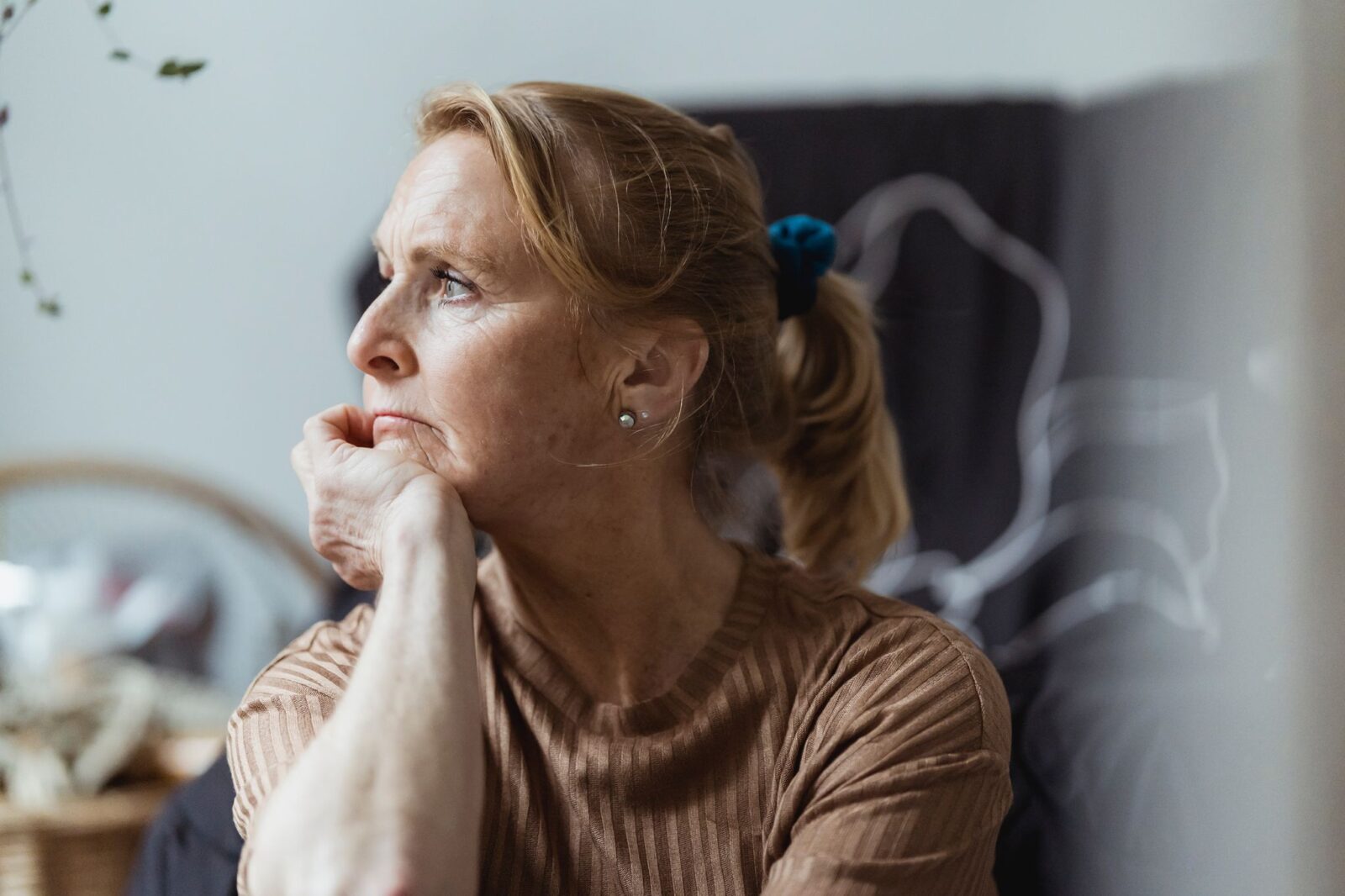 Ansiedade na perimenopausa: mulher de meia-idade pensativa, com a mão no queixo, olhando para o lado