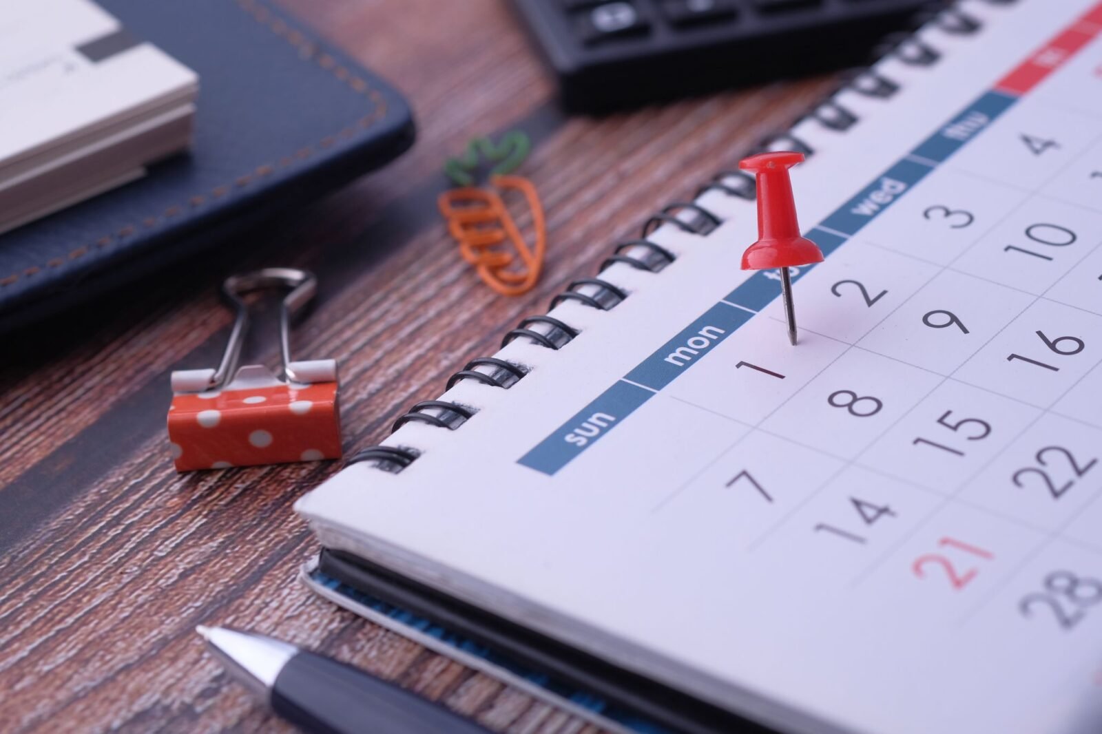 Calendário de mesa com caneta e clipes para planejar os blocos de tempo da semana