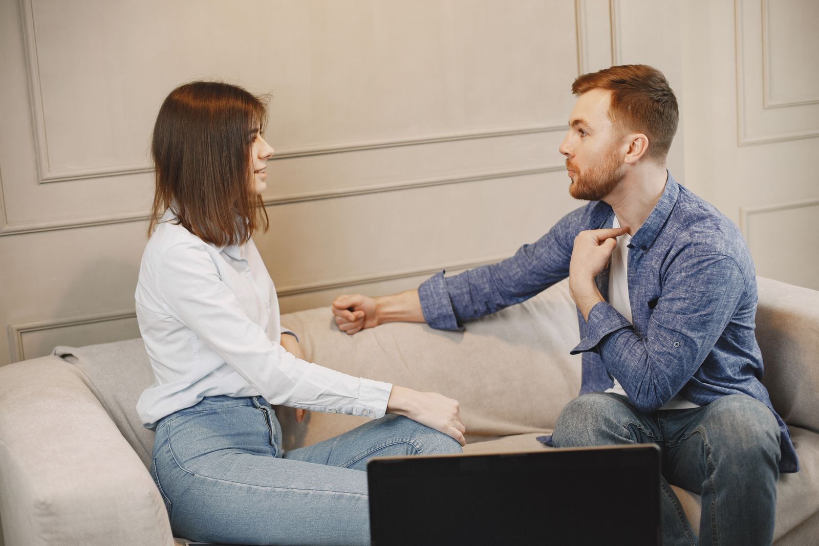 Casal sentado no sofá conversando, de frente um para o outro