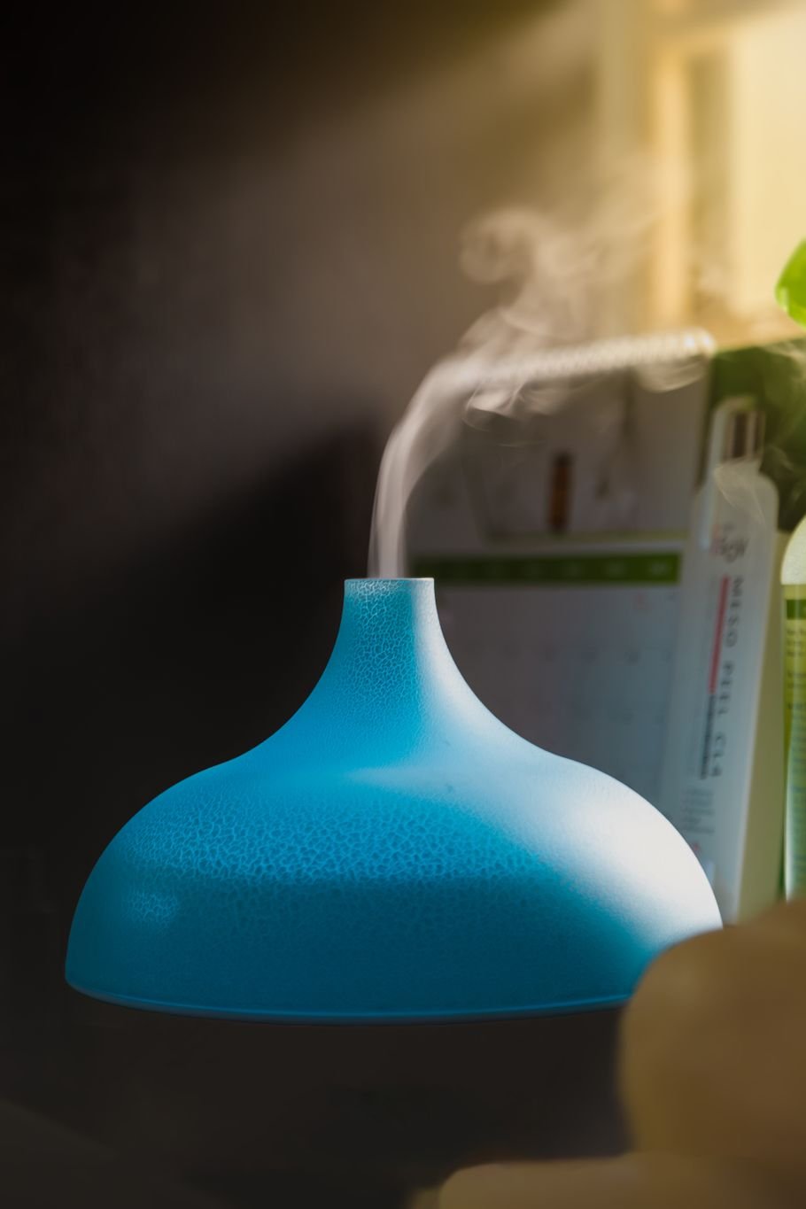 Difusor de aromas portátil azul liberando névoa perto de uma janela