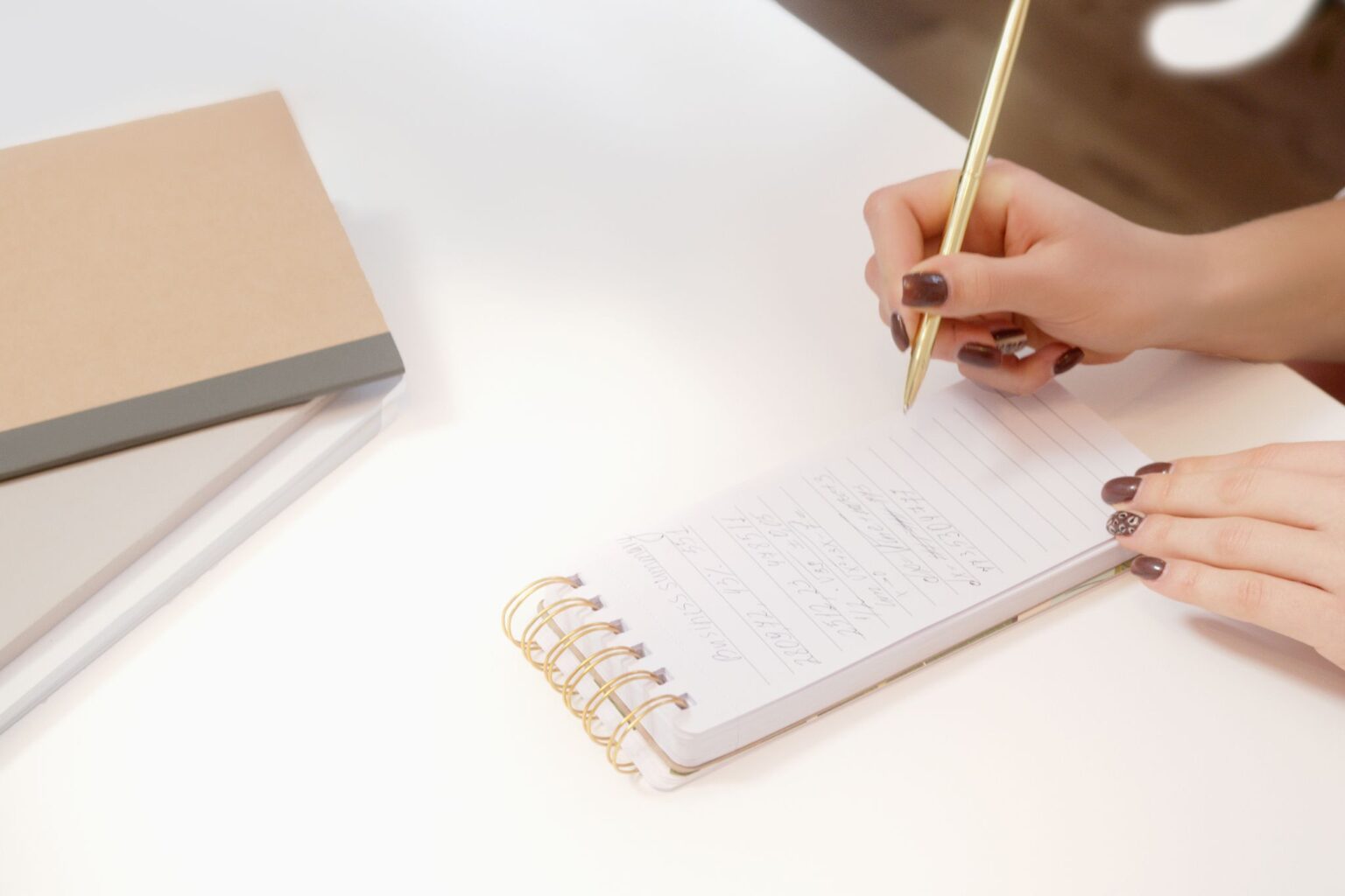 Mão escrevendo em um caderno sobre a mesa