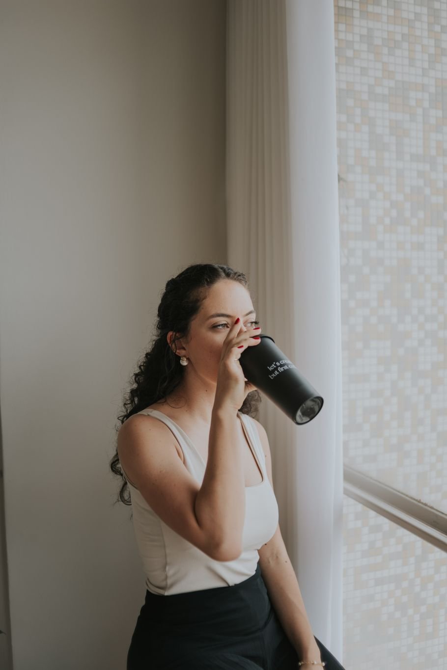Slow living na rotina: mulher fazendo uma pausa para beber algo quente perto da janela