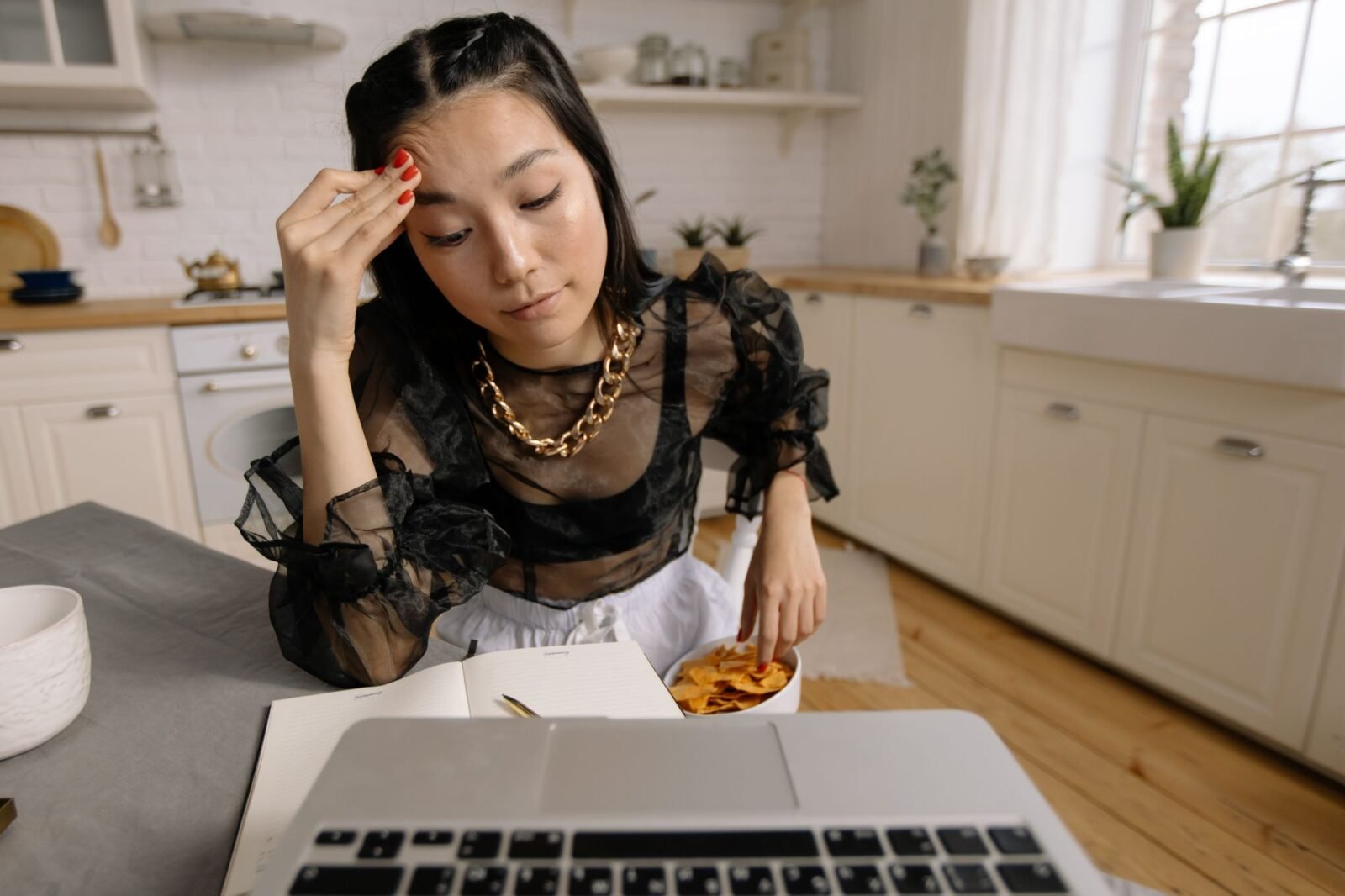 Carga mental: mulher cansada sentada à mesa da cozinha com um caderno aberto