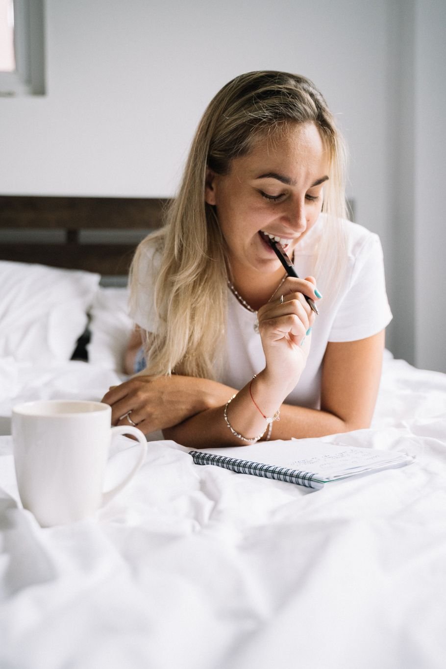 Morning pages na prática: mulher escrevendo num caderno na cama, com uma caneca ao lado