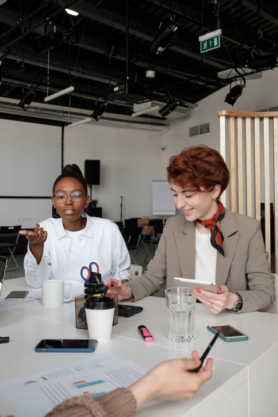 Assertividade no trabalho: mulher expondo uma ideia em reunião, com colegas à mesa