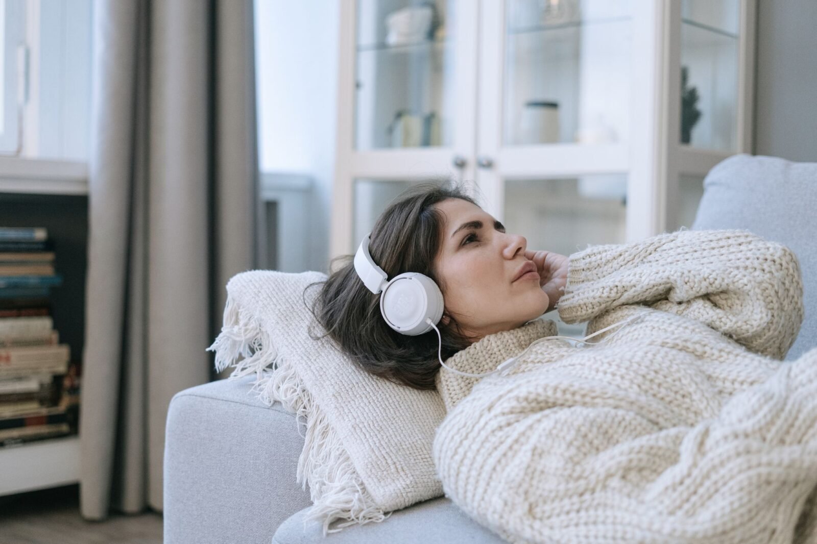Pessoa altamente sensível descansando no sofá com fones de ouvido depois de um dia cheio de estímulos