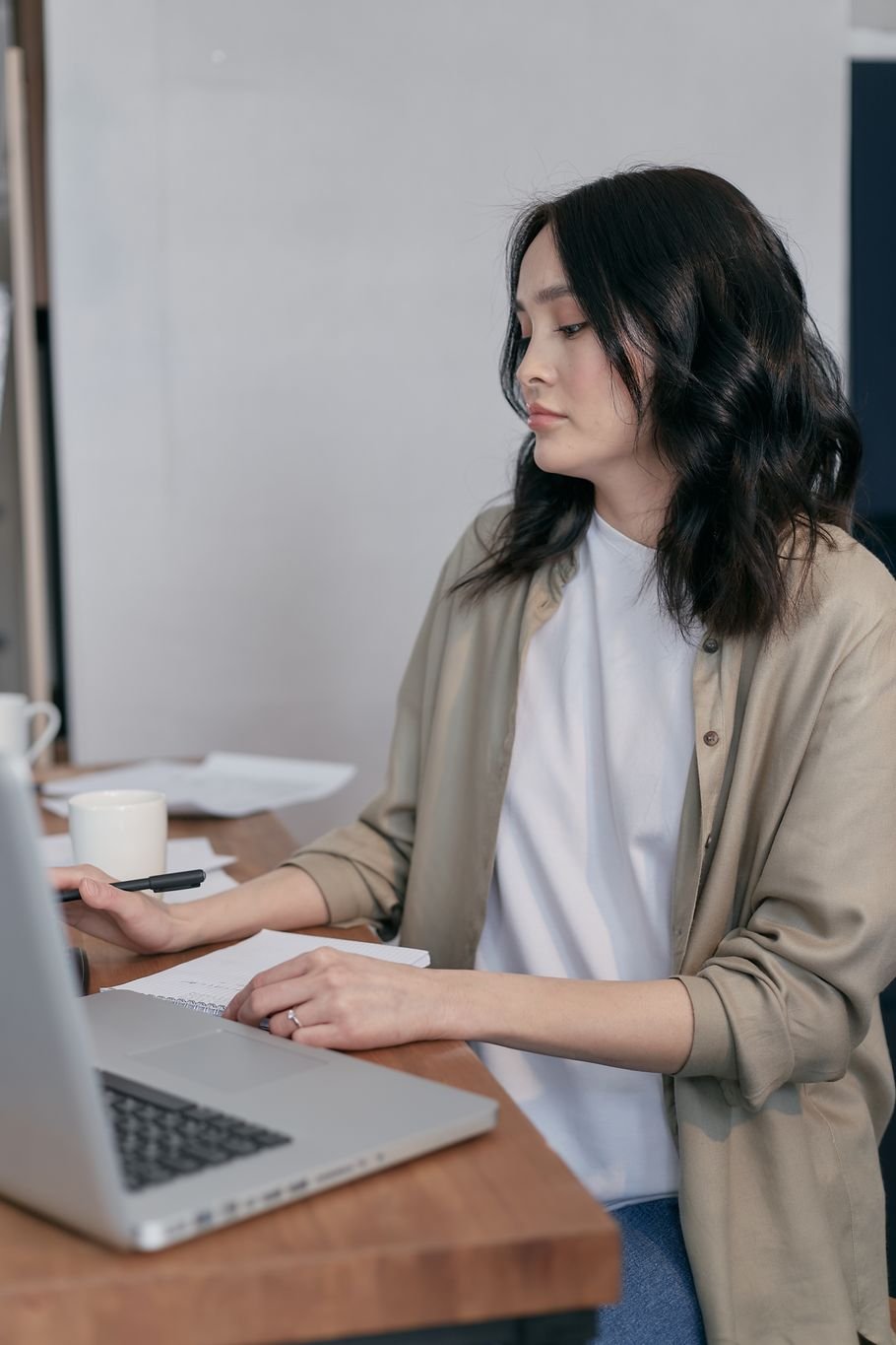 Síndrome do impostor no dia a dia: mulher séria diante do notebook, com papéis na mesa