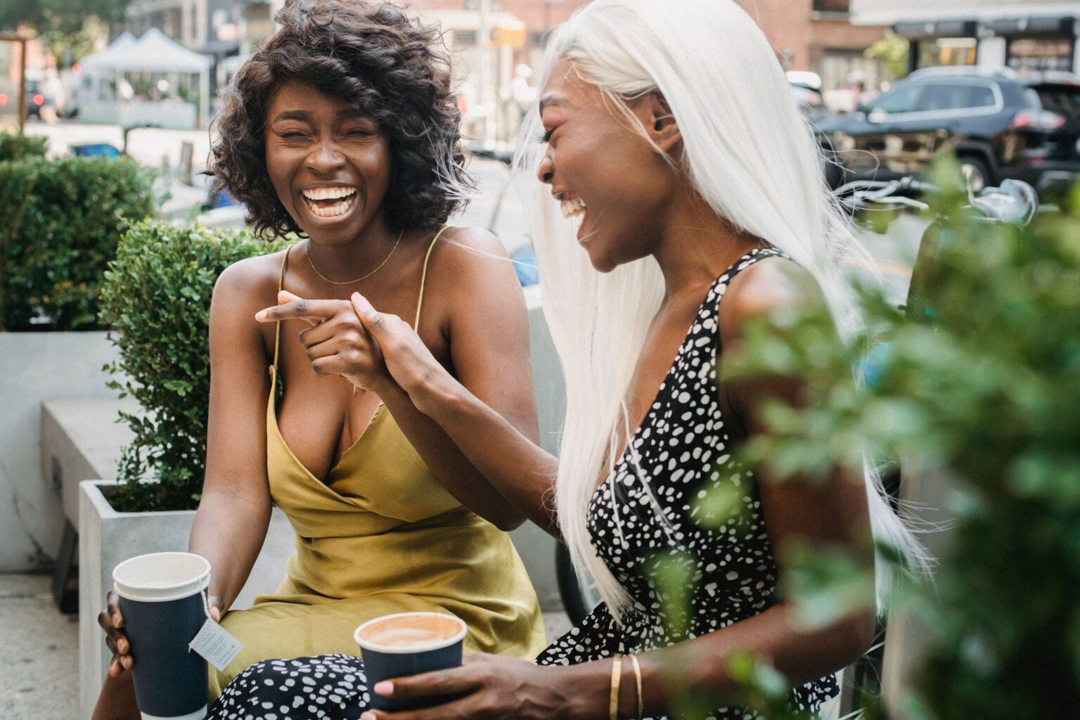 Inveja: duas amigas rindo juntas enquanto tomam algo
