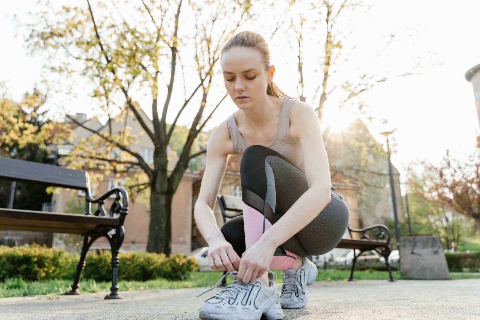 Motivação: mulher amarrando o tênis antes do treino no parque