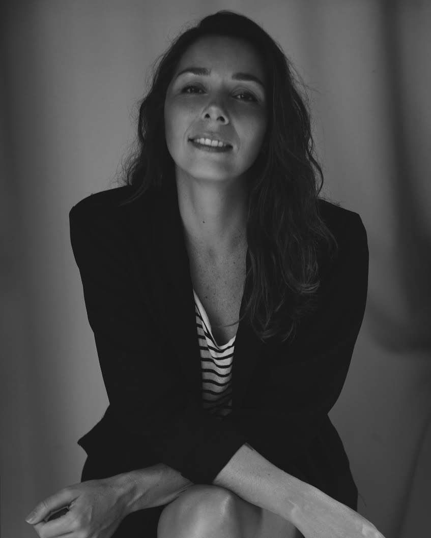 Retrato em preto e branco da psicóloga e psicanalista Adriana Prosdocimi, sorrindo, sentada